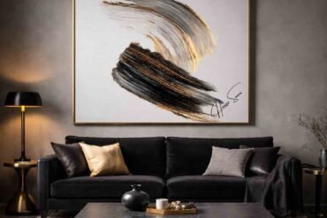Emotional interior design featuring black, gold, and gray abstract artwork above a black velvet sofa in a moody luxury living room.