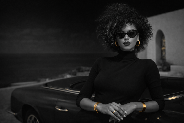 Black woman in a high-end grayscale editorial portrait with subtle gold accents, reflecting too many ideas and not enough follow-through through a poised, disciplined, luxury visual style.